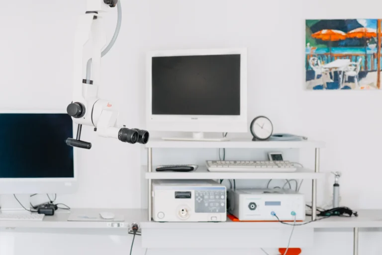 Ein Mikroskop steht vor einem Computer und medizinischen Geräten in einem hellen, natürlichen Raum