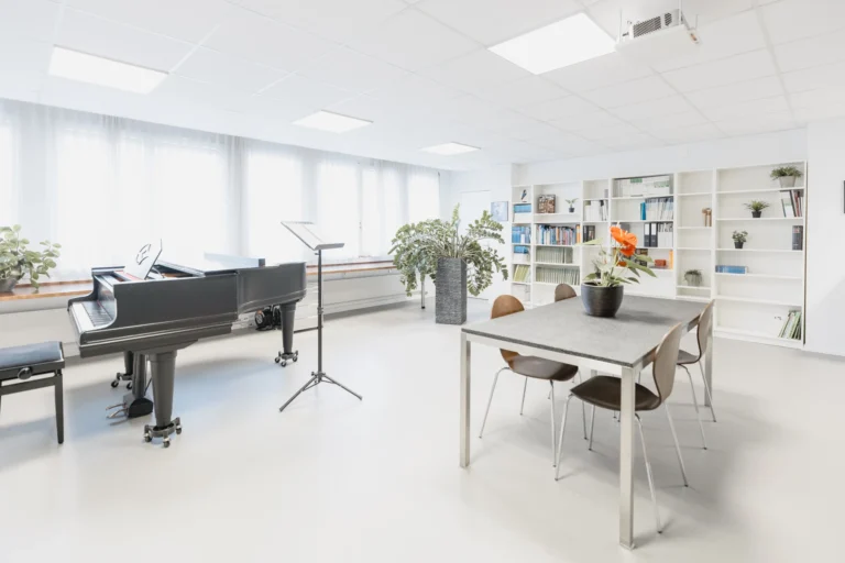 Grosser Raum mit Klavier, Tisch, Bücherregal, Pflanzen und Notenständern