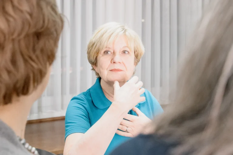 Dr. med. Salome Zwicky im Gespräch mit zwei Patientinnen; ihre Hände sind auf Halshöhe erhoben, um etwas zu veranschaulichen.